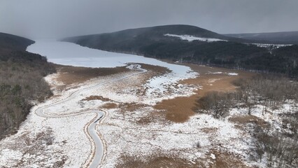 Ancient Glacier finger lake Hemlock Lake, NY during Winter in freezing conditions ideal for ice fisherman landscape with cloud shadows on snow covered lake