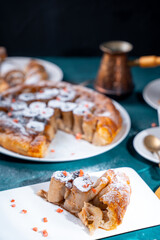 A slice of bread with butter and a cut loaf on a wooden board on a white table and background.