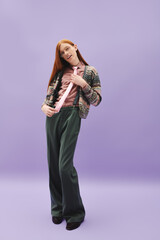 Stylish young man with red hair showcases modern queer fashion against a vibrant backdrop