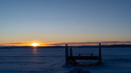 Sunrise Over Frozen Lake-A tranquil sunrise over the frozen Khuvsgul Lake in Mongolia, with a wooden structure adding contrast to the vast icy landscape.