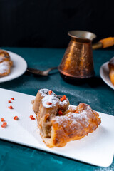 A piece of banana cake or pie and a cup of Turkish coffee on a white plate on a turquoise background. French dessert on the table. Vertical photo.