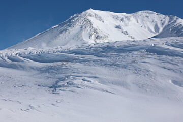 シュカブラが覆う斜面の向こう側に見える旭岳山頂
