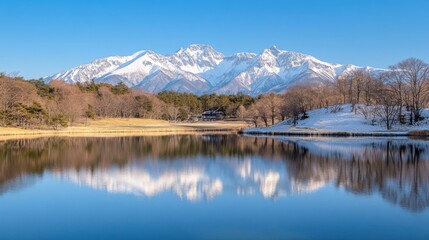 Majestic snow-capped mountains reflecting in calm lake under clear blue sky