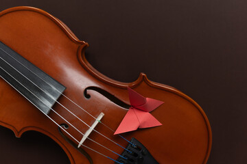 Fototapeta premium A paper butterfly on a wooden violin, representing the beauty of creativity and liberty. Creative, music, and innovation themes.