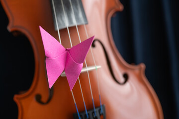 A paper butterfly on a wooden violin, representing the beauty of creativity and liberty. Creative,...