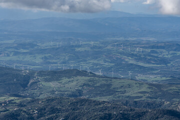 Fototapeta premium Wind Turbines on a Scenic Landscape for Renewable Energy. A scenic view of rolling hills with multiple wind turbines generating clean energy, promoting renewable energy sources.