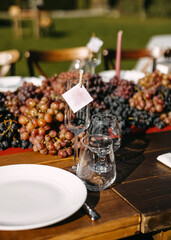 A close-up of a rustic outdoor dining table set for a vineyard-themed event