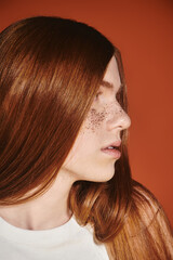Confidently showcasing modern queer style with vibrant red hair and unique freckles