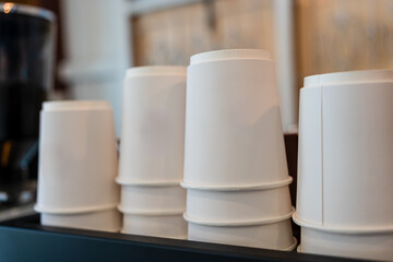 White paper coffee cup stacking in rows above coffee machine