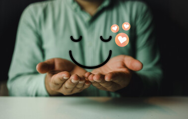 Businessman use hand holding icons of happy smile face and red heart emotion, think positive. Client satisfaction surveys and review.