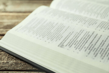 Open Holy Bible in English language on wooden table, closeup