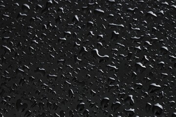 Water drops on black glass surface, closeup