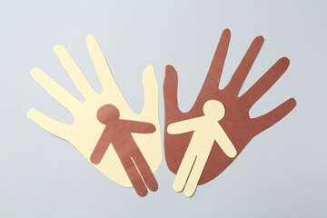 Stop racism. Hands and human paper figures of different colors on light grey background, top view
