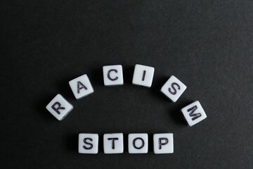 Phrase Stop Racism made with beads on black background, top view