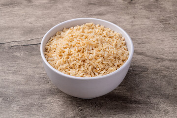 Cooked brown whole rice in a bowl over wooden table