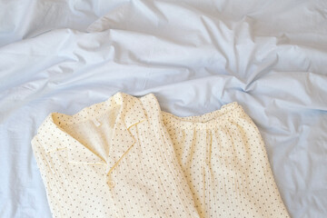 Close-up of pajamas lying on a bed with pastel blue bed linen. Сopy space. Concept of soft, cozy,...