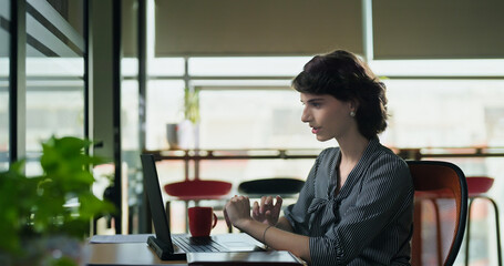 Young adult woman lady sitting use laptop look screen do work online video call client talk new plan indoor office gen z busy expert female girl agent distant help speak share idea job centre place	