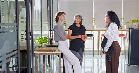 Indian young adult women intern old aged lady hold cup mug drink coffee talk gossip work place...