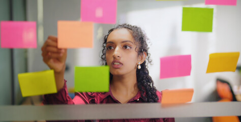Close up of Indian young adult gen z woman lady read new notes look task data day time office glass...