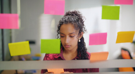 Close up of Indian young adult gen z woman lady read new notes look task data day time office glass...