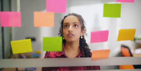 Close up of Indian young adult gen z woman lady read new notes look task data day time office glass...