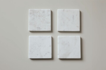 Four white square marble tiles coasters mockups isolated on textured beige wooden table background. Natural stone blocks, podiums objects. Creativity concept. Artwork template display.