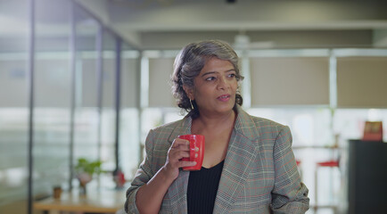 Indian happy old aged boss ceo woman lady hold cup drink coffee routine tea spend break time...