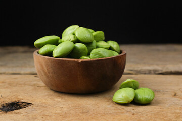 Close-up of Fresh Green Stink Beans in a Rustic Wooden Bowl