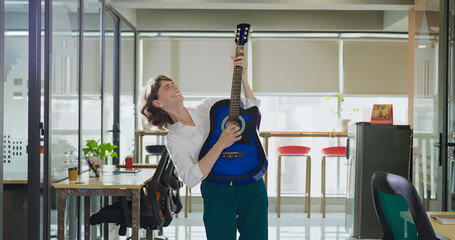 Indian Asian gen z business woman lady person play music guitar sing song indoor office Happy cute...