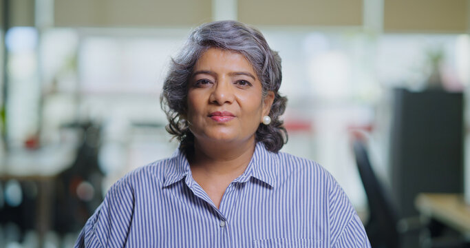 Indian Asian gen x old aged older woman lady look cam do work talk chat share idea new plan online video call office head shot view elder adult expert female speak make vlog shoot day blog job place