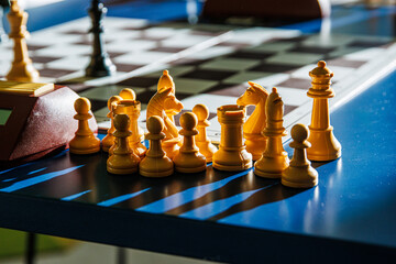 Chess pieces in sunlight on a blue tournament table after the endgame. Closeup of white chess...