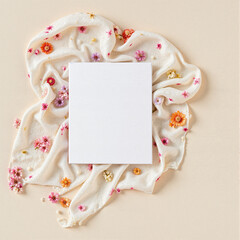 Blank paper sheet surrounded by a floral scarf on a neutral background with copy space