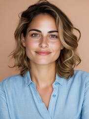 Caucasian young adult female smiling in blue shirt against peach background.