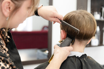 Skilled stylist gives a stylish haircut to a young boy in a modern salon setting