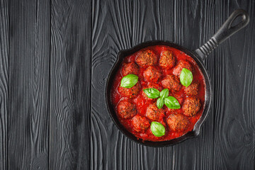 delicious traditional Italian meatballs polpette in a cast iron skillet on a black slate rustic...
