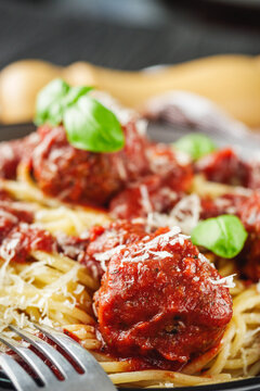 delicious traditional Italian meatballs polpette with spaghetti pasta on a black wooden rustic background