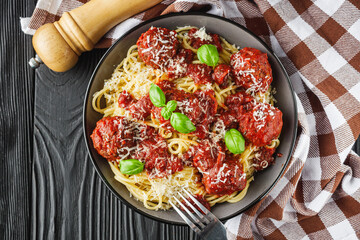 delicious traditional Italian meatballs polpette with spaghetti pasta on a black wooden rustic background