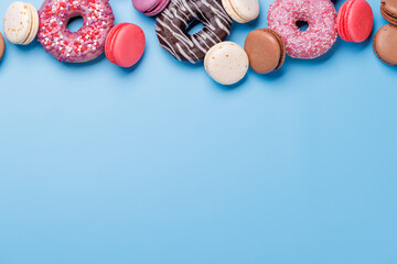 An assortment of colorful sweets, including donuts, macarons, and candies, arranged on a vibrant blue background