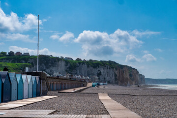 Beach with a row of small blue and white beach houses. The beach is empty and the sky is clear,...