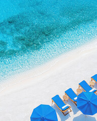 Naklejka premium Luxurious beach with blue loungers and umbrellas by clear ocean
