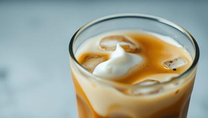 a close-up of a glass of iced coffee with cream swirling in