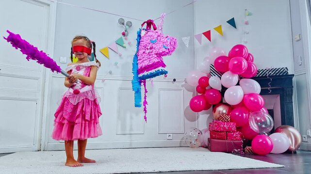 Birthday fun as a blindfolded girl hits colorful unicorn pinata