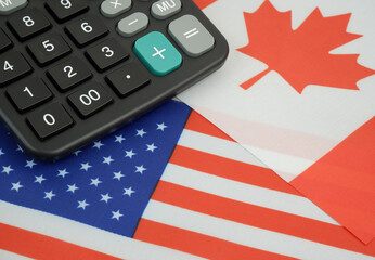 Economic rules between the United States and Canada. USA and Canadian flags with black calculator.