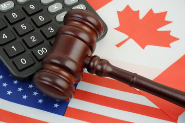 Import tariffs between United States and Canada. US and Canadian flags under judge gavel and calculator.