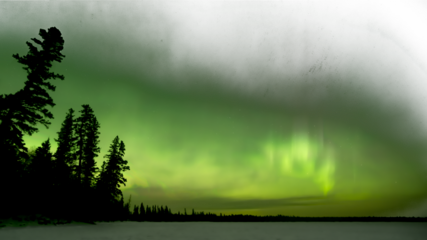 Muted colored northern lights aurora fading to transparent above a northern forest and lake
