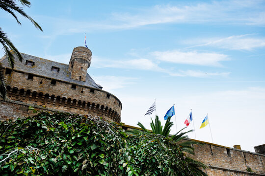Flags wave atop a historic stone castle at Saint-Malo, France