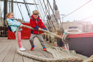 Energetic kids enjoy tugging a hefty rope on deck of pirate ship