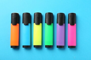 Bright highlighters on light blue background, flat lay