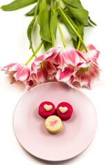 Romantic background of pink and white tulips and a dessert plate of petit fours.