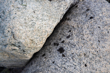 Close-up view of granite rocks showcasing intricate textures and natural patterns under warm daylight. The setting conveys a tranquil ambiance in nature.